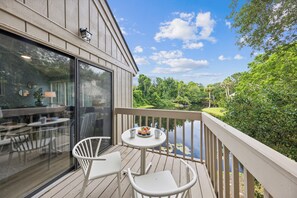 Relax and unwind in the stylish living area and attached deck, featuring plush furnishings and panoramic views of the lush landscape beyond.