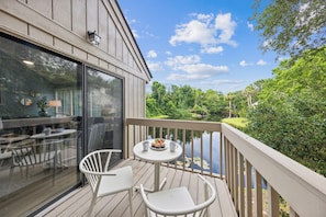 Relax and unwind in the stylish living area and attached deck, featuring plush furnishings and panoramic views of the lush landscape beyond.