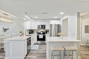Renovated kitchen with sleek stainless steel appliances and a large island with bar seating.