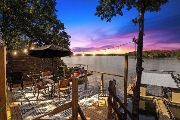 Unwind on the deck with breathtaking lakeside views! Enjoy magical sunsets, cozy string lights, and a peaceful outdoor dining area.