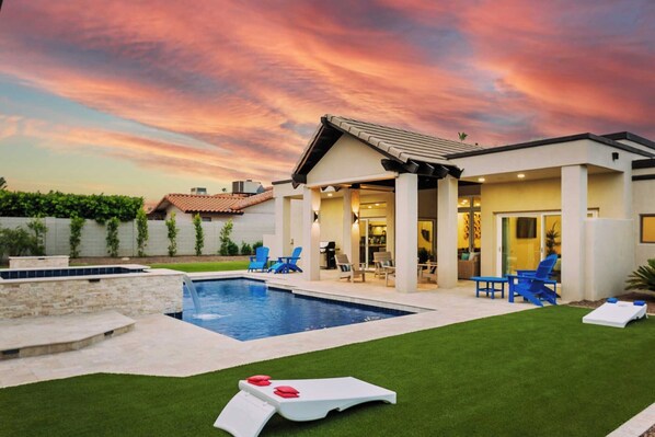 Backyard with pool, spa waterfall, and corn hole setup