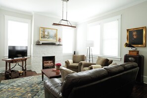 Large living room outfitted with a clean leather sofa and the most comfortable oversized chairs, oil paintings, and many interesting antiques to take you back in time.