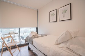 Cozy bedroom with balcony access, perfect for enjoying morning coffee with a view.