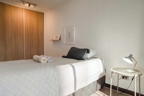 Relax in this cozy bedroom with modern decor and ample storage, perfect for a restful stay.