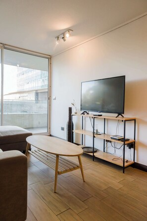 Relax in this modern living room with a flat-screen TV and natural light from the balcony.