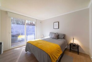 Cozy bedroom with natural light and modern decor, perfect for a relaxing stay.