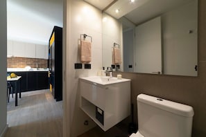 Sleek bathroom with modern fixtures and a peek into the stylish kitchen, perfect for a comfortable stay.
