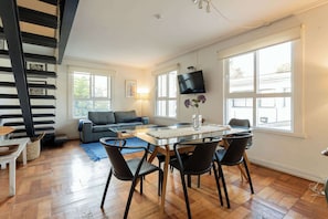 Bright and modern living space with a sleek dining area, cozy sofa, and abundant natural light, perfect for relaxation.
