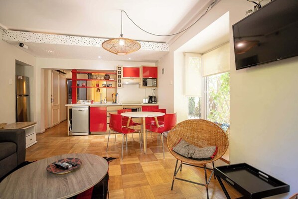 Bright and modern kitchen with vibrant red accents and a cozy dining area, perfect for enjoying meals with natural light streaming in.