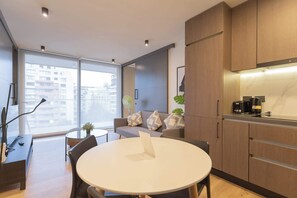 Experience urban living with a cozy sofa, modern kitchen, and stunning city views from the comfort of this stylish apartment.