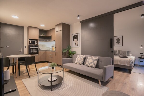 Modern open-plan living space with sleek kitchen and cozy bedroom, perfect for a stylish getaway.
