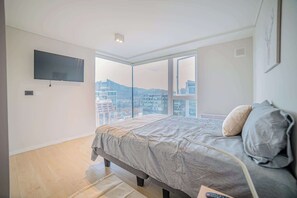 Relax in this cozy bedroom with stunning city views and modern amenities, perfect for unwinding after a day of exploring.