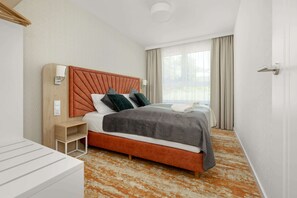 A bright bedroom with a double bed and a large window letting in plenty of natural light.