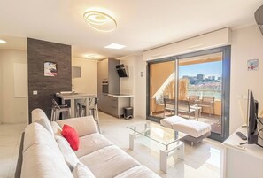 pièce principale avec salon, cuisine ouverte et terrasse