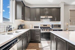 Cook In Style In Our Sleek Dark-Themed Kitchen, Featuring Modern Appliances And Elegant Finishes