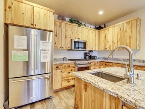 Kitchen equipped with KitchenAid appliances, including an oven, stove, microwave, and refrigerator/freezer. Features a stainless steel sink, upgraded cabinetry, and granite countertops for a modern, functional space.