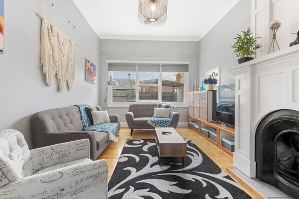 The warm and welcoming lounge room is complete with two cosy sofas and an armchair, offering the perfect spot to settle in with a movie. 
