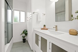 Modern bathroom with a hot shower and all the essentials, including shampoo, conditioner, and more.