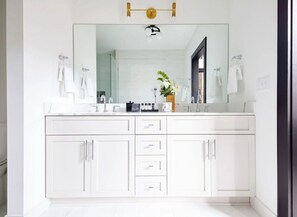 The primary bathroom offers sleek finishes, a soaking tub with Smart TV, walk-in shower, and plush towels. Spacious and private, it adds a luxurious touch to your suite—perfect for unwinding after a day in Downtown New Orleans.