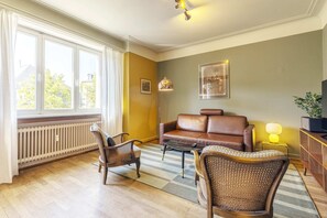 Bright and airy living room with large windows offering plenty of natural light. A cozy and stylish space to unwind and enjoy your stay in Luxembourg.