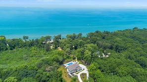 This aerial view captures the beauty of a house nestled amidst lush trees and serene waters.