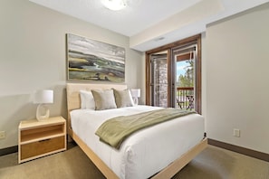 Primary bedroom with a queen bed, access to the patio & a private, ensuite full bathroom.