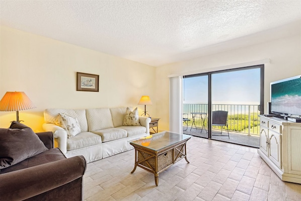 Bright, open living area with a neutral color scheme and plenty of natural light coming in through large windows.
