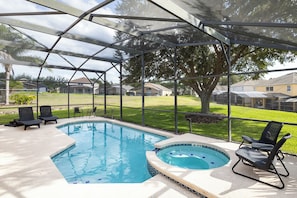 Orlando retreat: pool, hot tub, and lounge chairs under a serene lanai