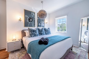 This King Suite exudes a contemporary charm, featuring a soothing color palette of whites and grays complemented by pops of vibrant blues. This Suite comes with a private bath and TV - and combines comfort with elegance, making it an ideal retreat for relaxation.