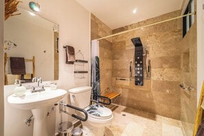 Accessible private bathroom with elevated toilet seat ADA, grab bars around toilet and shower, sliding door for bathroom, shower seat and hand-held shower with rain shower