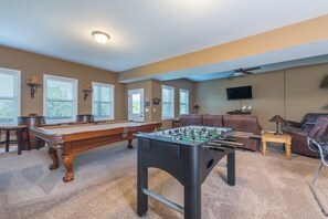 Game room on lower level with a pool table, foosball table, and arcade games.