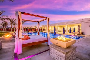 Luxury daybed cabanas and a firepit lounge area with panoramic views of the desert sky at dusk.