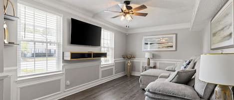Relax in the plush living room with ample seating, a ceiling fan, and a Samsung Smart TV for all your entertainment needs.