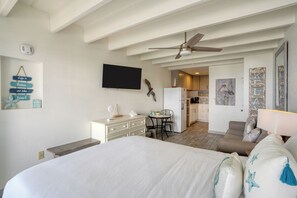 Charming coastal-themed room with a cozy bed, modern TV, and kitchenette.