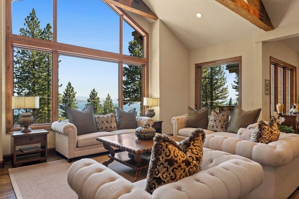 Relax in this elegant Lake Tahoe living room featuring stunning floor-to-ceiling windows with breathtaking forest and lake views.