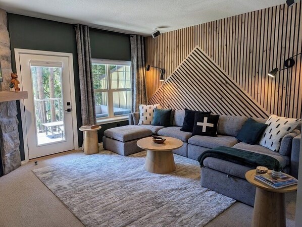 Large couch with two movable ottomans. Hand-crafted cedar planking along the wall.