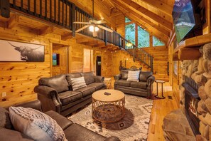 Welcome to our cabin living room! Gather around the natural stone gas fireplace, perfect for cozy evenings, and enjoy ample seating while catching your favorite shows on the flat-screen TV.