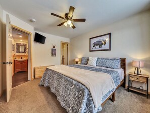 Spacious primary bedroom featuring a king-size bed, ceiling fan for comfort, 32" TV, and an attached bathroom for added convenience