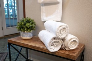 Charming wooden tabletop with neatly arranged white hand towels and a tasteful plant accent