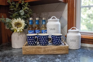 Coffee essentials in a delightful setup, including blue porcelain mugs and a fresh flower vase.