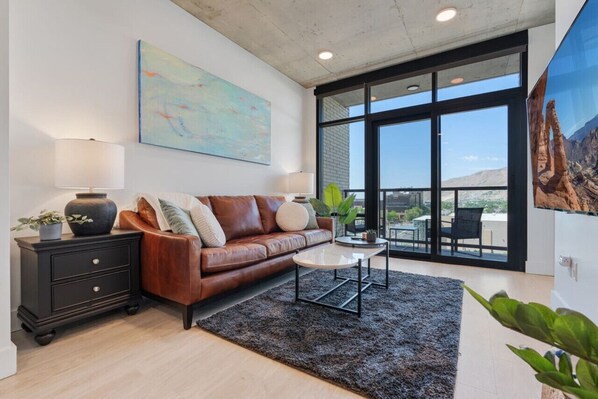 Beautifully designed living room. 65" TV, leather sofa and amazing views of mountains and city skyline.