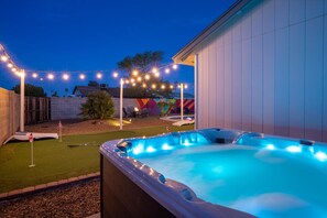 Experience nighttime magic in the hot tub, with string lights and fun backyard games in view