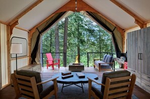 Relax in this spacious glamping tent with a comfortable seating area and breathtaking forest views.