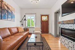 Stylish living room with a leather sofa, modern decor, and a cozy fireplace, perfect for unwinding after a day of exploring.