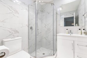 The family bathroom has a glass shower, vanity and toilet.