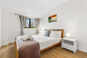 On either side of the bed are matching wood nightstands, each topped with lamps that cast a warm, inviting glow.