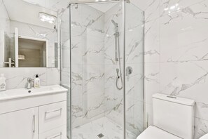 The family bathroom has a glass shower, vanity and toilet.