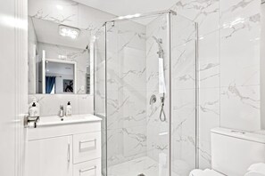 The family bathroom has a glass shower, vanity and toilet.