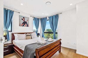 On either side of the bed are matching wood nightstands, each topped with lamps that cast a warm, inviting glow.