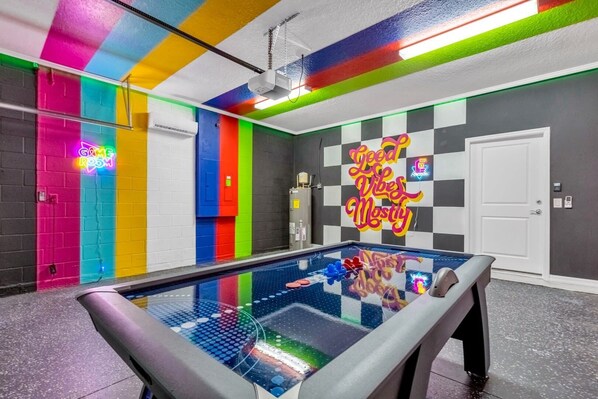 Dive into fun in this vibrant game room with air hockey and neon vibes—perfect for lively gatherings!